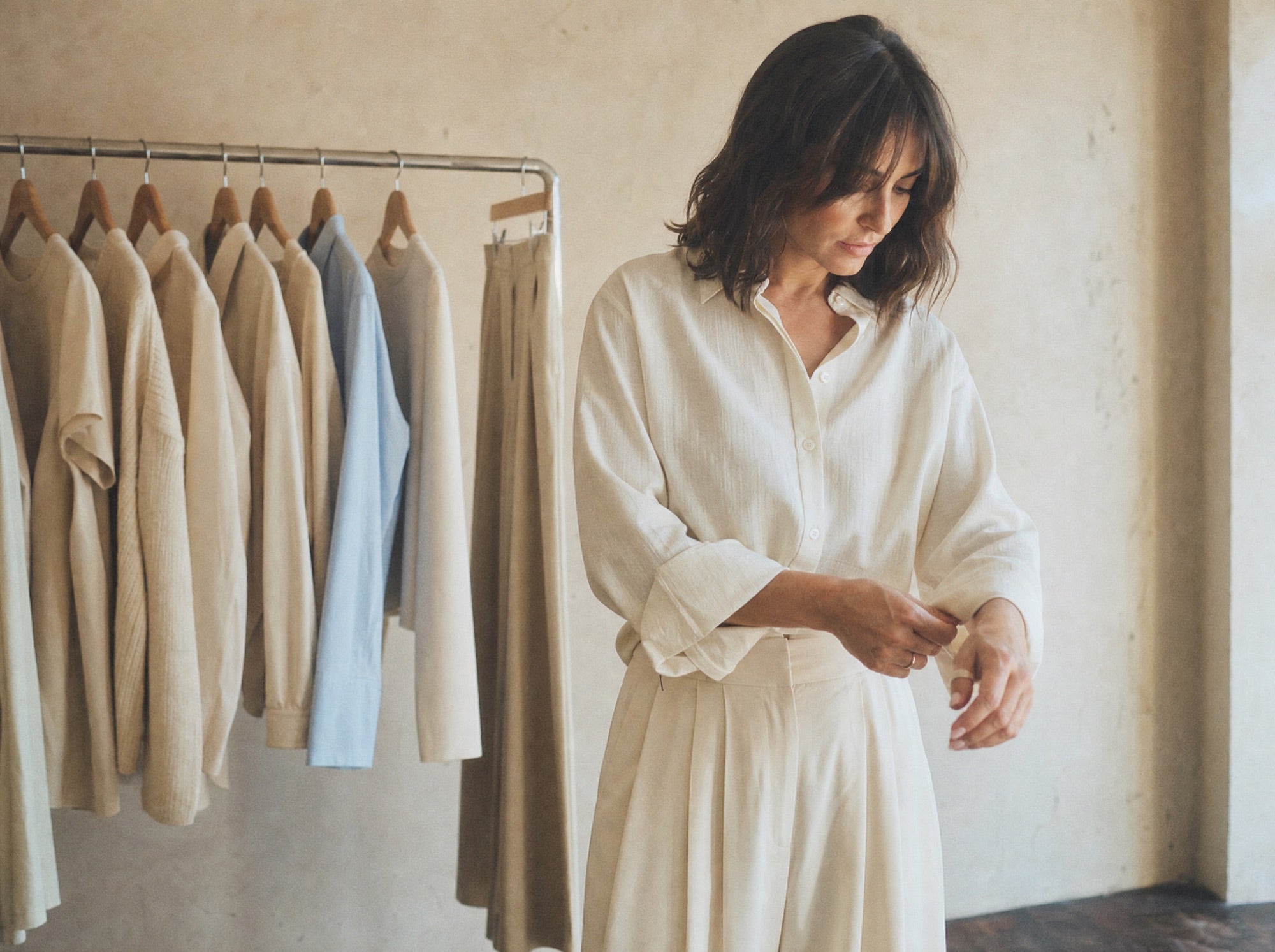 Azurelle studio image, woman beside a rail of cream and beige garments
